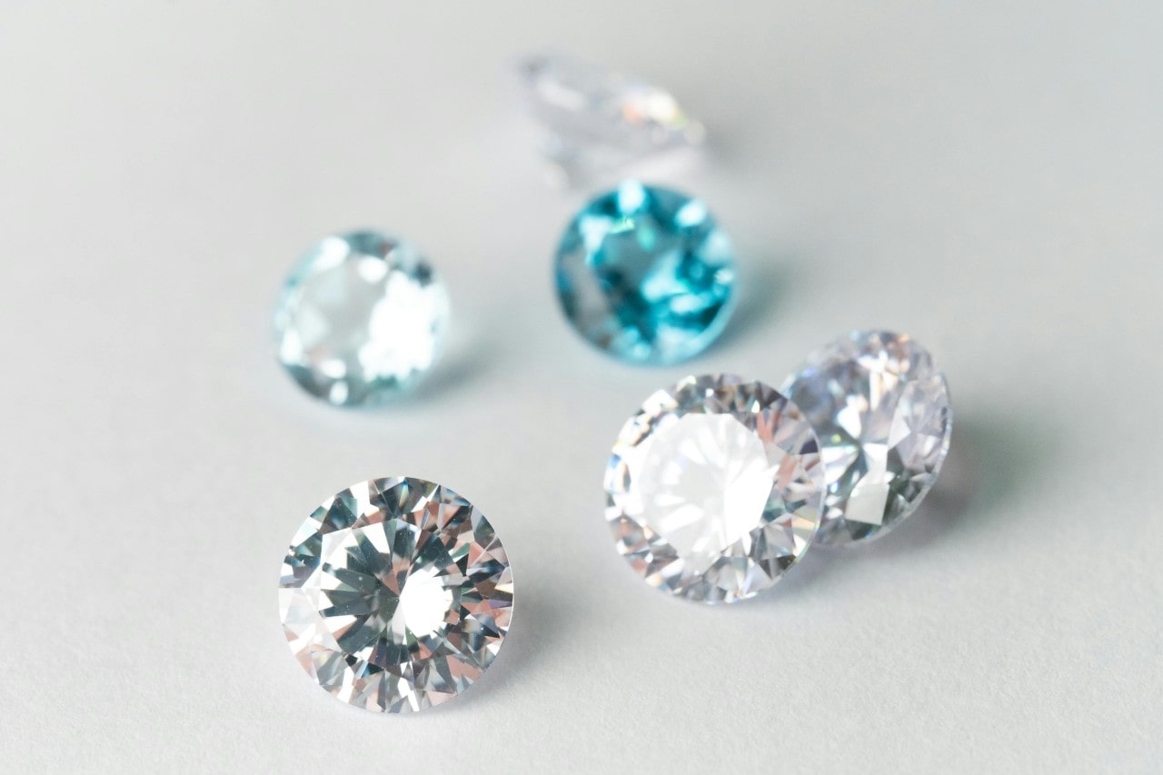 six round cut diamonds, two of which are blue, on a white surface