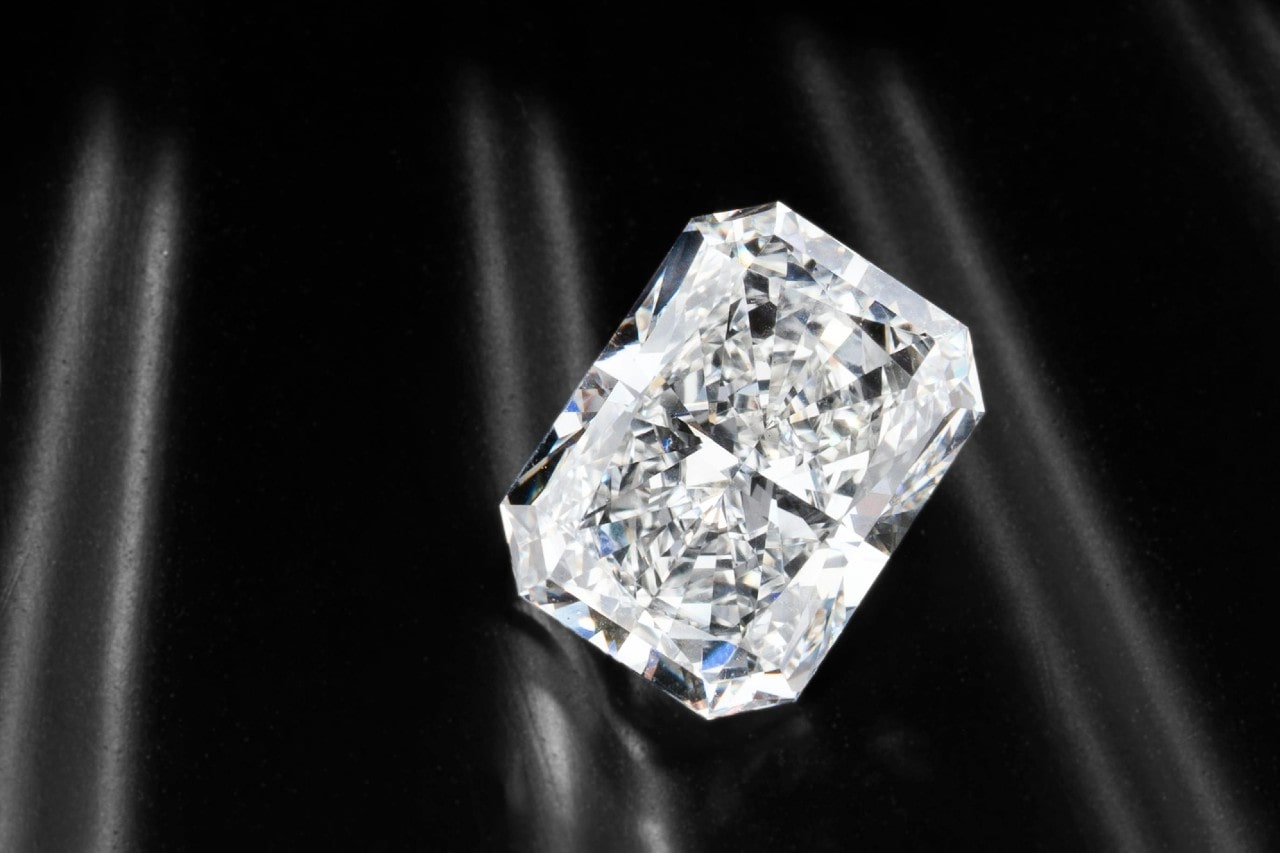 close up image of a radiant cut diamond on a black shiny surface