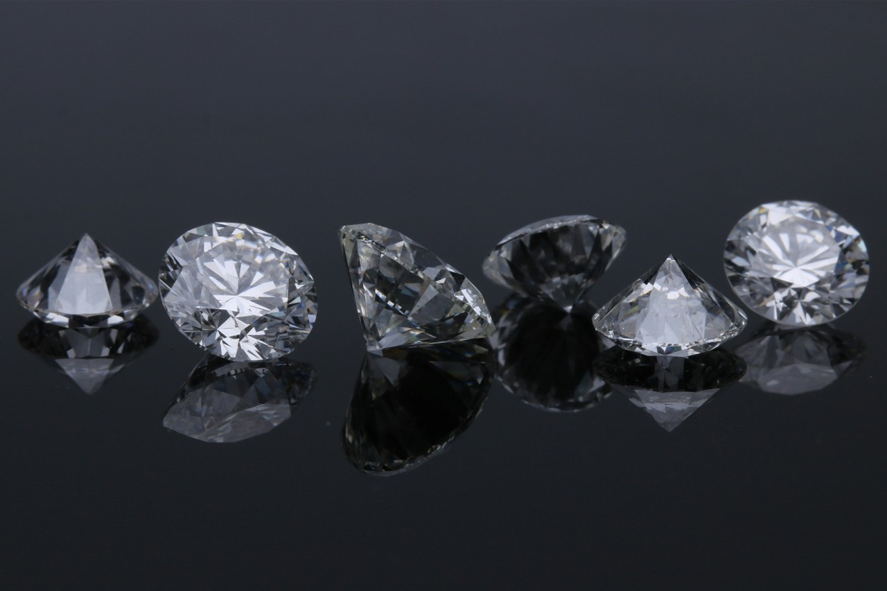 six round cut diamonds in a line on a reflective black surface