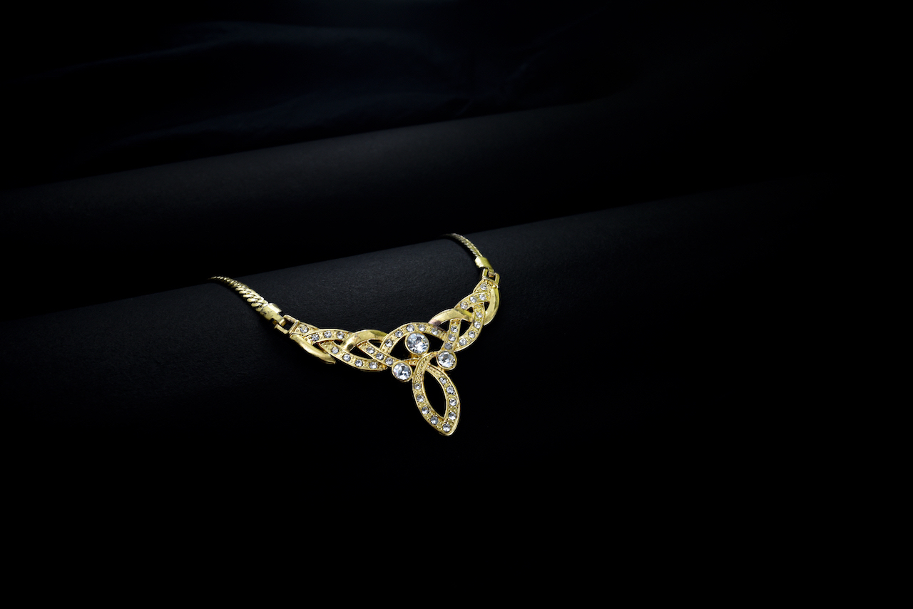 gold diamond necklace on black background